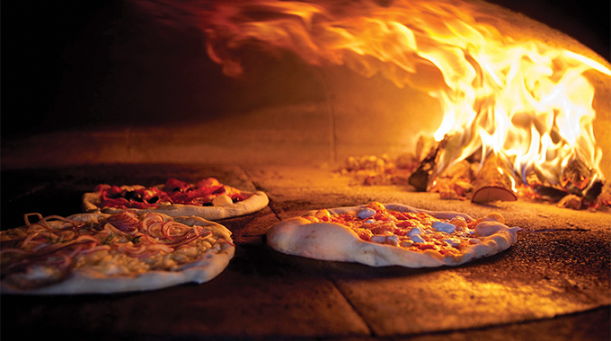 Pizza cooking inside a wood-fired oven.