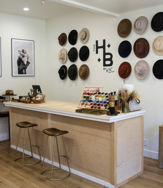 Interior of Hat Bar by Kate Kaney, with hats on the wall and colorful embellishments to choose from on the counter.