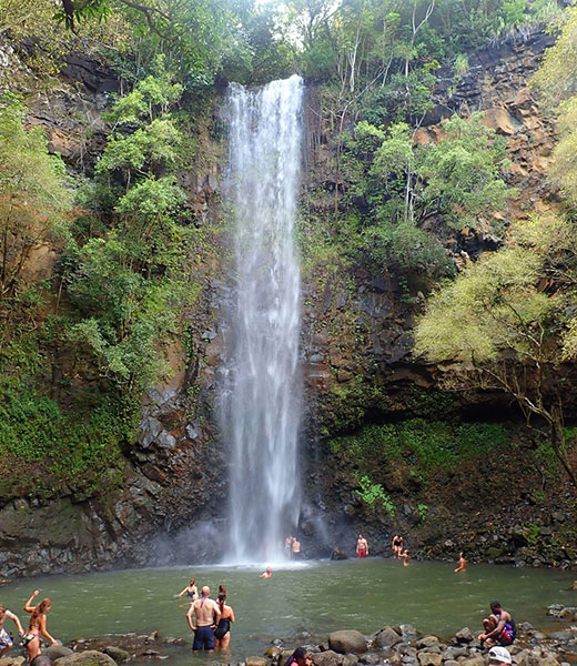 People swimming at the base of Uluwehi Falls